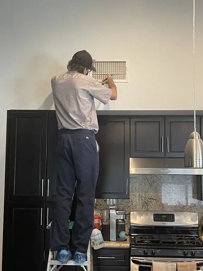Technician inspecting an air vent during HVAC service in Vadnais Heights